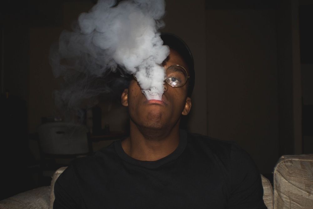 man exhaling cloud of cbd smoke