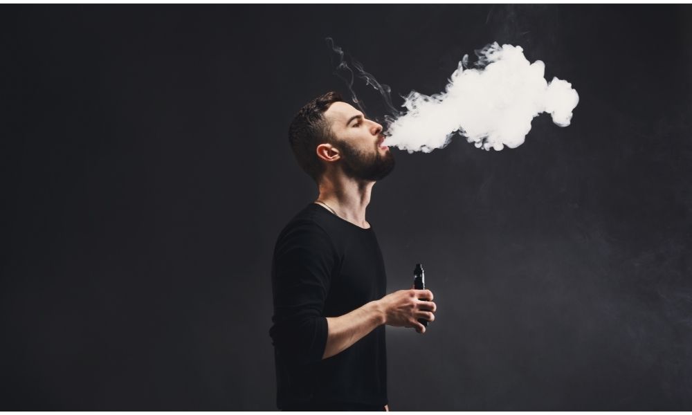 bearded man exhaling vape smoke