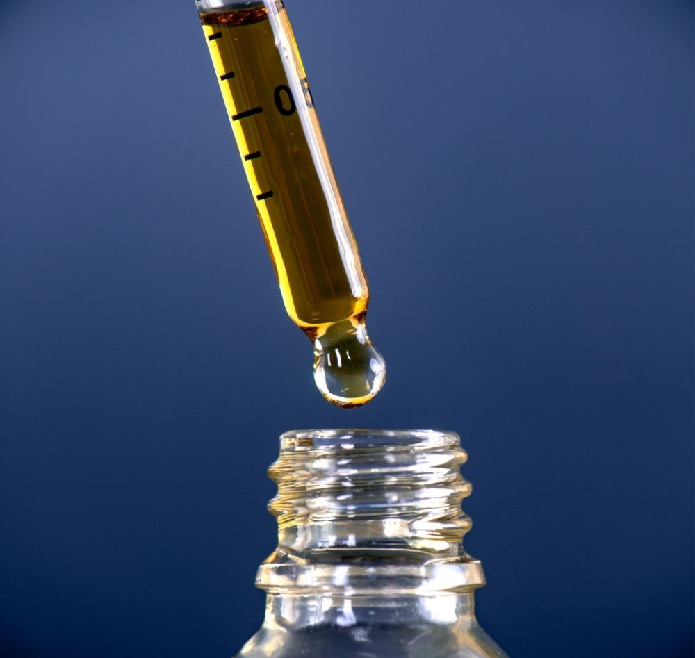 cbd oil dropper with blue background