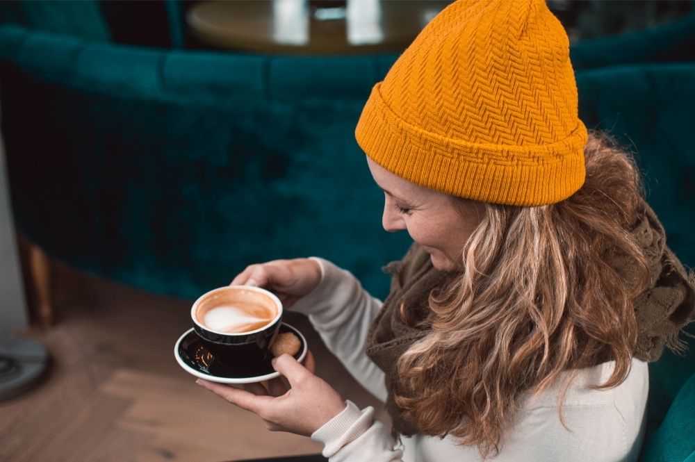 woman in orange beanie staring at coffee